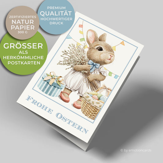 Süße Osterkarte im Hochformat. Kleiner Hase mit roten Schuhen trägt einen Palmkätzchenbund. Neben dem Hasen steht ein Geschenk und ein bunter Osterkorb.