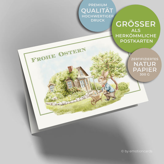 Süße Osterkarte mit feinem Doppelrahmen in Grün, kleiner Osterhase im Garten mit Schubkarre und Korb mit Ostereiern, kleines Haus und Baum im Hintergrund