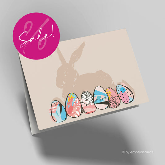 Moderne Osterkarte, hellbrauner Hintergrund mit brauner Hasensilhouette und bunte Ostereiern im Vordergrund.