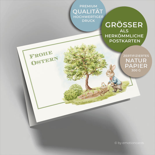 Süße Osterkarte mit feinem Doppelrahmen in Grün, kleiner Osterhase im Garten mit Schubkarre und Korb mit Ostereiern, Baum mit Karottenbeet im Hintergrund