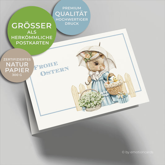 Süße Osterkarte mit feinem hellblauen Doppelrahmen, Frohe Ostern, Süße Hasendame mit hellblauem Kleid und Sonnenschirm, trägt Osterkorb mit kleinem gelben Küken und Ostereiern darin